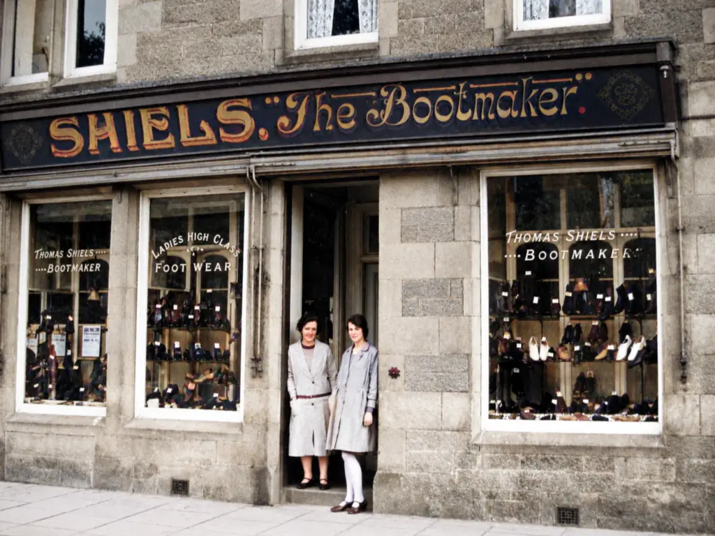 Shiels the Bootmaker, Biggar — Mary “Moll” Shiels stands at the left in the shop doorway. Moll eventually inherited the family business from her uncle Thomas and operated it until her retirement in the early 1960s.